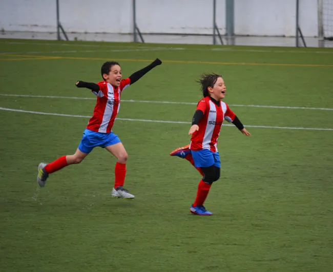 Junior soccer athletes celebrate on the pitch.