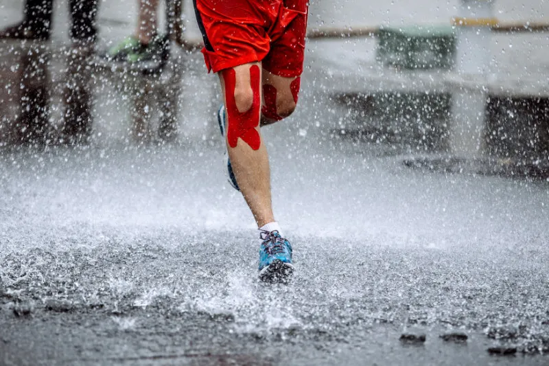 A male athlete with kinesiology tape applied around his knee