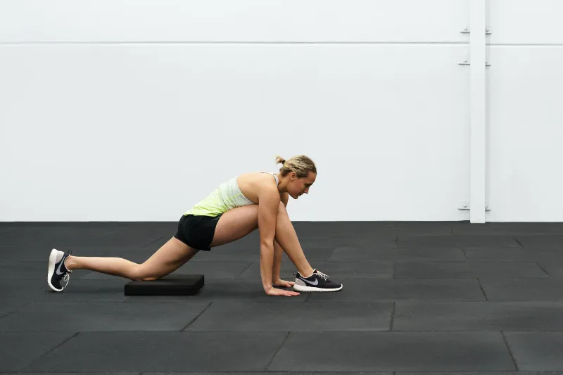 An athlete performing an adductor and hip stretch for her Osgood Schlatter knee pain
