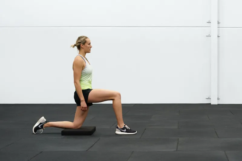 An athlete performing a hip flexor stretch for her Osgood Schlatter knee pain