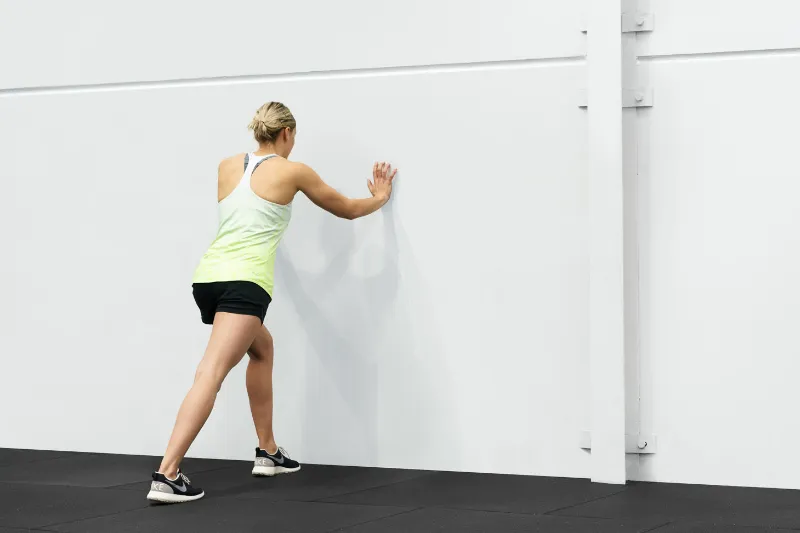 An athlete performing a calf stretch for her Osgood Schlatter knee pain