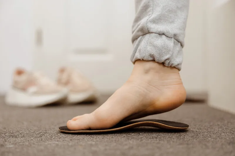 A child's bare foot resting on a moulded orthotic insole