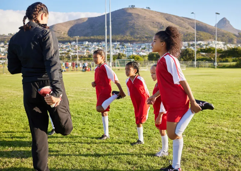 Children warming up for Soccer practice with their coach.