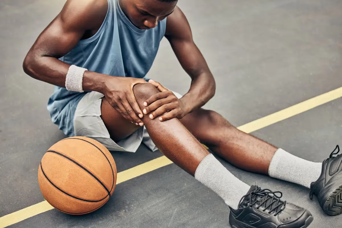 A young basketball player holding a painful knee